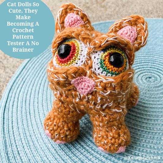 photo of a crocheted orange cat doll with big rainbow eyes on a sky blue spiral mat