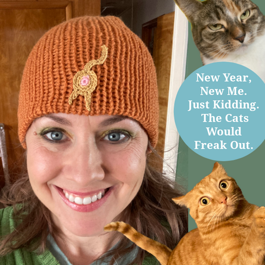 photo of a smiling lady in an orange knit hat with a gold cat butt on the front. An orange cat is on the side looking like he ate catnip and a smug tabby is peeking out from the corner