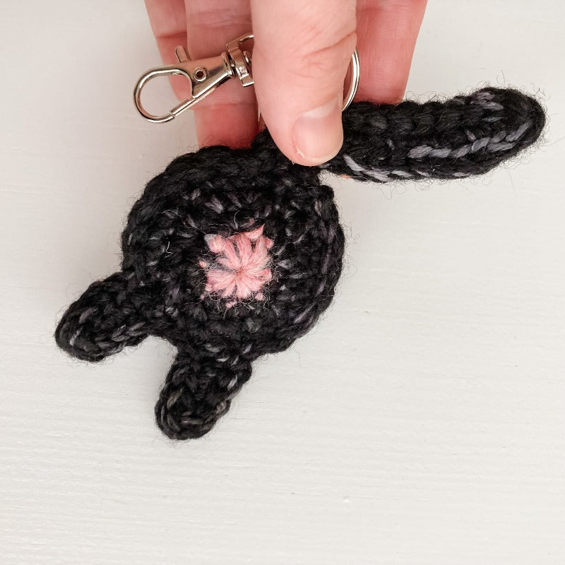 black cat butt keychain in a hand for scale