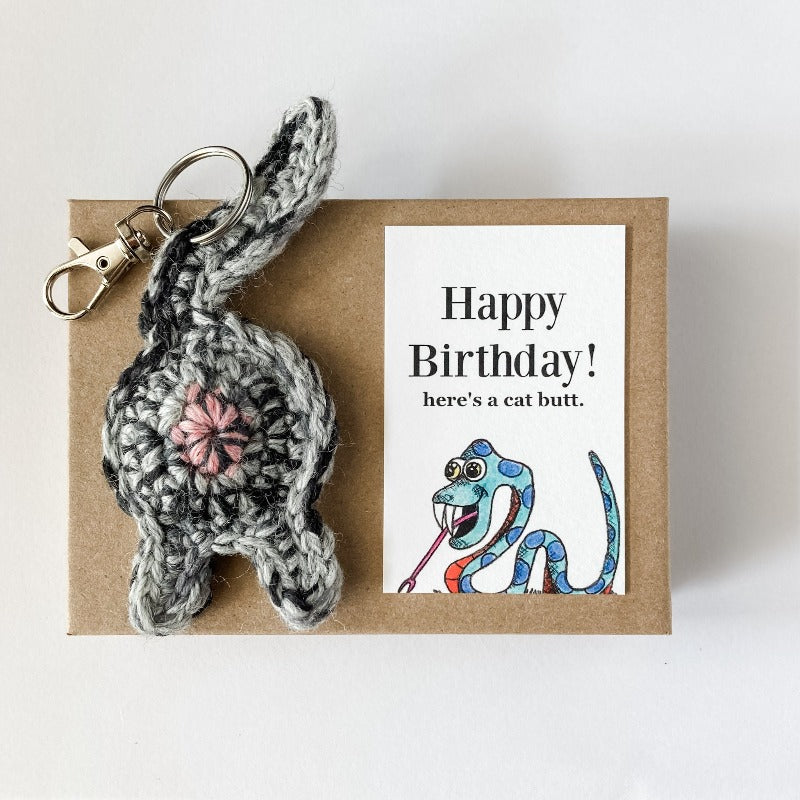 gray cat butt keychain with funny snake birthday card on a Kraft box
